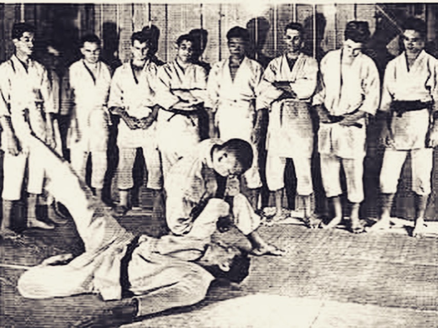 Prof Okazaki doing an armlock on uke on ground in front of jujitsu students